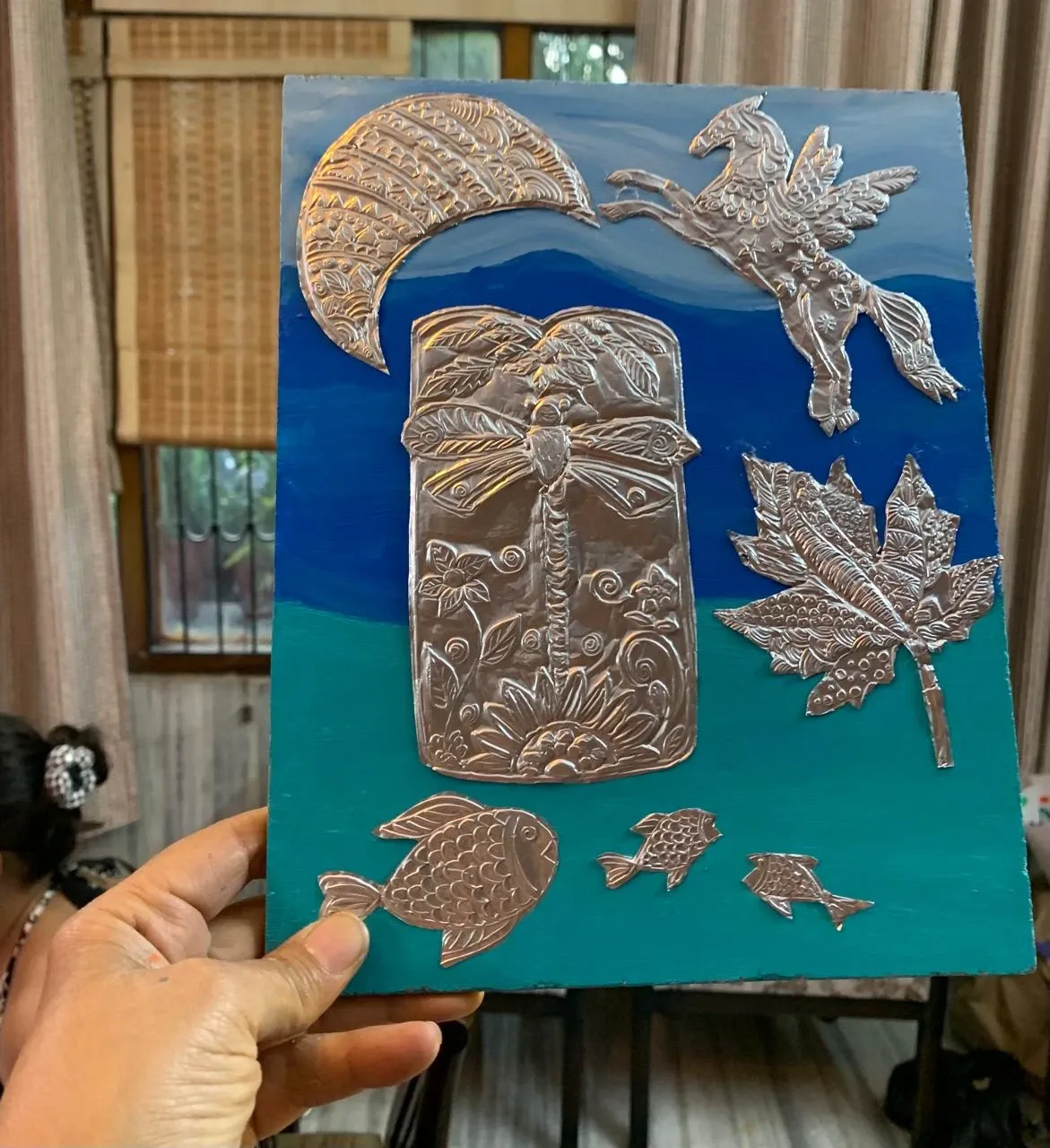 Embossed silver tin moon, horse, leaf and fish on a blue painted board